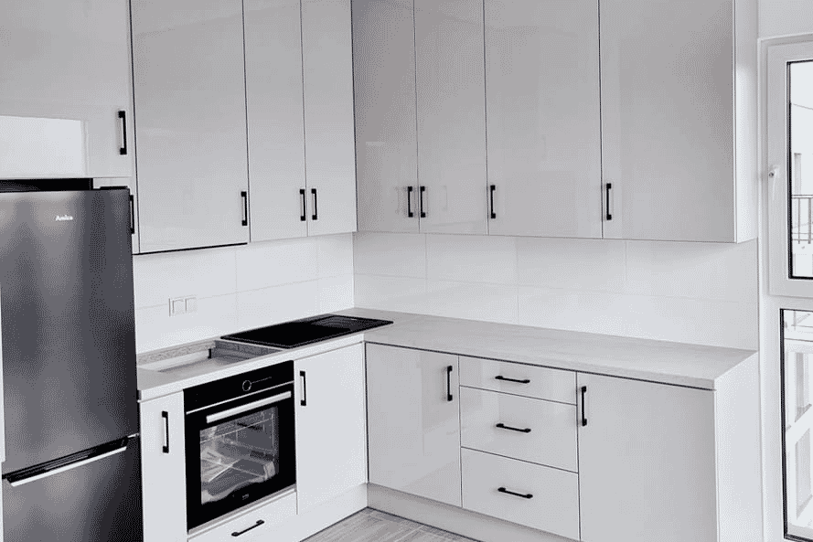 Zdjęcie jasnoszarej błyszącej kuchni z białymi blatami i czarnymi klamkami. Stworzone przez stol-max tychy patrycjusz wybraniec